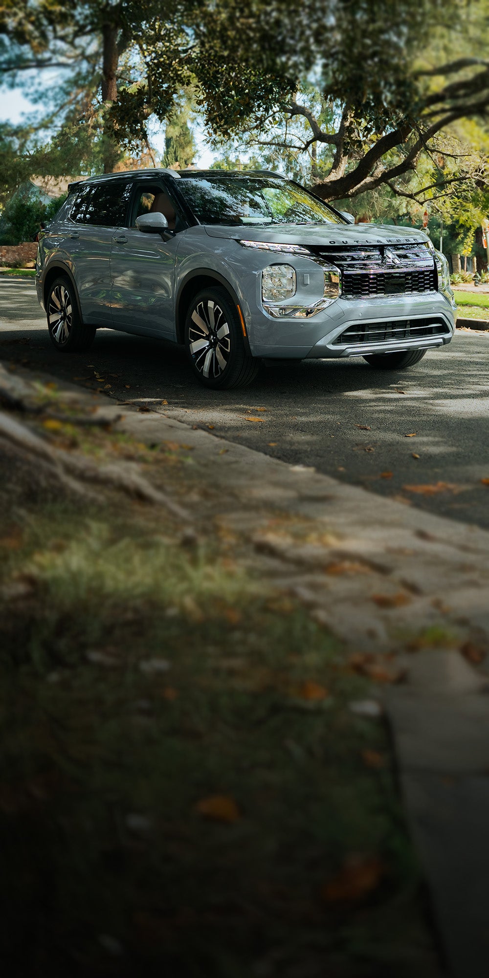 SUV Mitsubishi Outlander 2026 blanco estacionada en una entrada frente a una casa